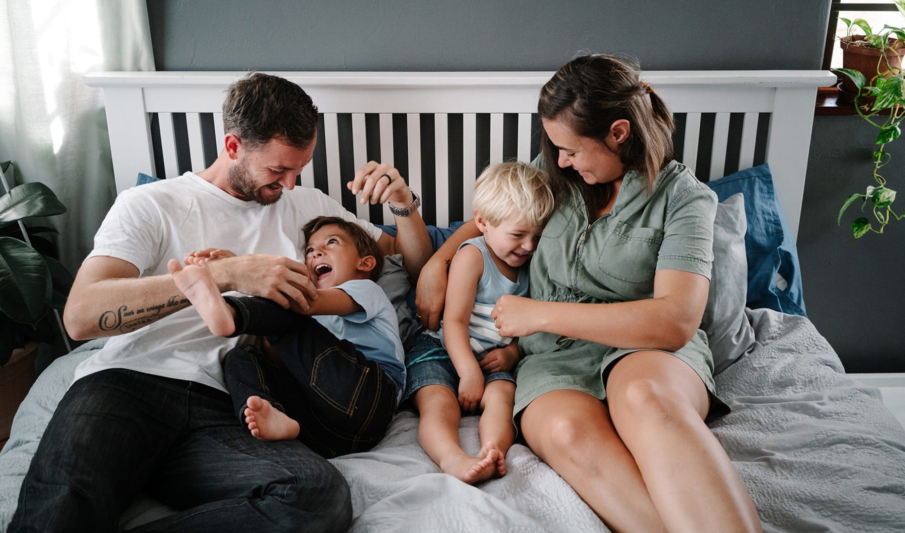 couple laughing in bed with children